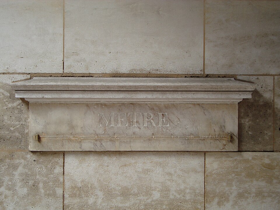 Metro-padrão de mármore com a palavra MÈTRE gravada, numa parede de Paris